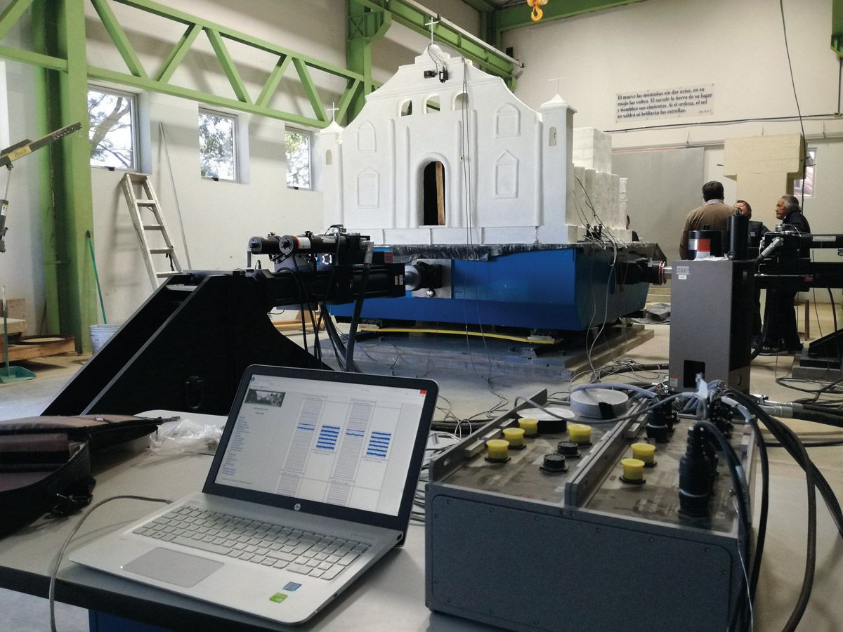 White scale model church on a shake plate inside a lab. A laptop is in the foreground to control the test.